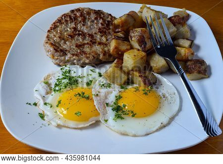 Fried Eggs Top With Parsley And Served With Sausage Patty And Home Fries,