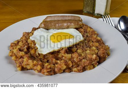 Corn Beef Hash With A Fried Egg With Two Sausages On A Table
