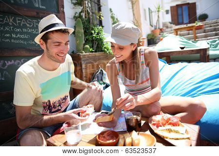 Couple of tourists having finger food in cosy place