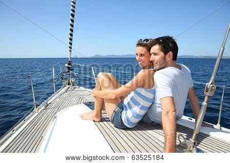 Couple stting on sailboat deck looking at sealine