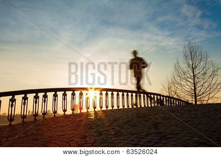 Jogger Running In Sunrise Over Bridge