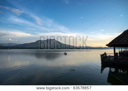 Fisherman in a boat in Lake Batur, a volcano crater lake in Bali Island, Indonesia.  The active volcano, Mount Batur is in the background.