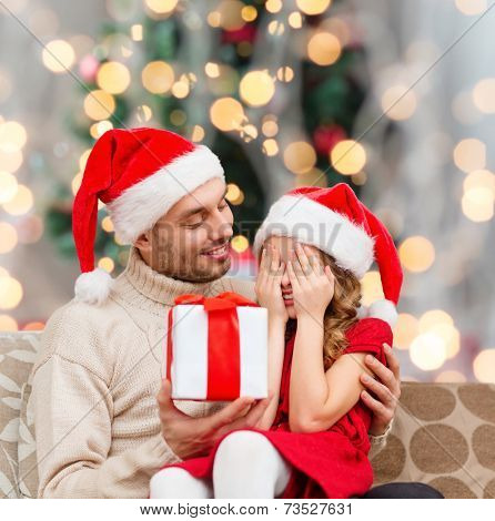 family, winter holidays and people concept - smiling daughter with closed eyes waiting for present from father over living room and christmas tree background
