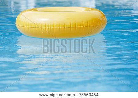 floating ring on blue water swimpool with waves reflecting in the summer sun