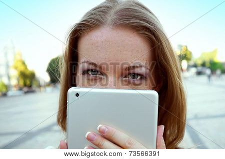 woman hiding her face behind tablet computer