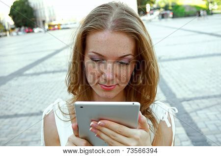 Pretty young  woman  using tablet pc outdoors on urban background