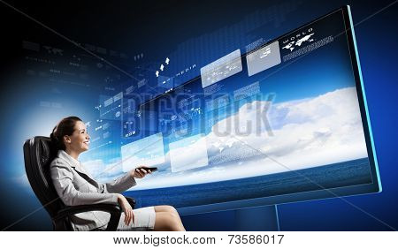 Young businesswoman in chair near tv screen with click