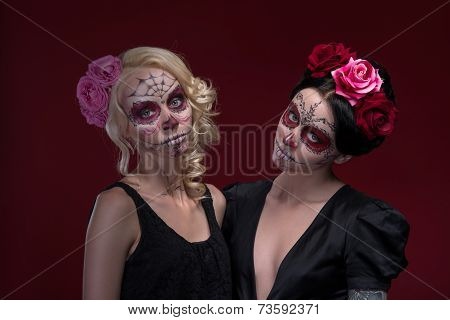 Portrait of two young girls in black dresses with Calaveras make