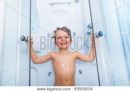 Happy little boy taking shower with soap on hair