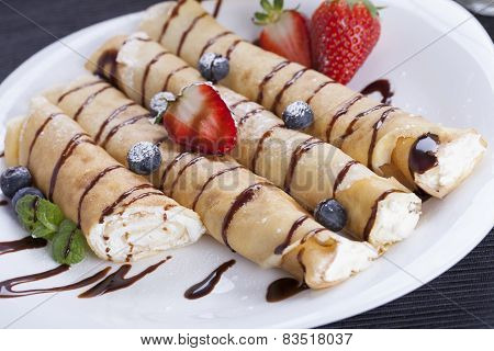 Delicious Sweet Rolled Pancakes On A Plate With Fresh Fruits