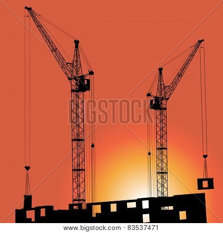 Silhouettes of crane on building against