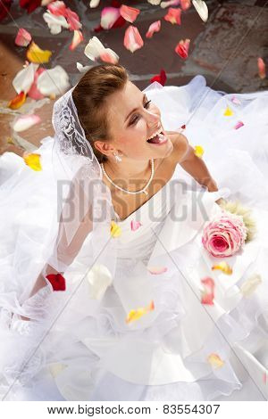 Happy Laughing Bride Sitting Outdoors On The Floor With Petals