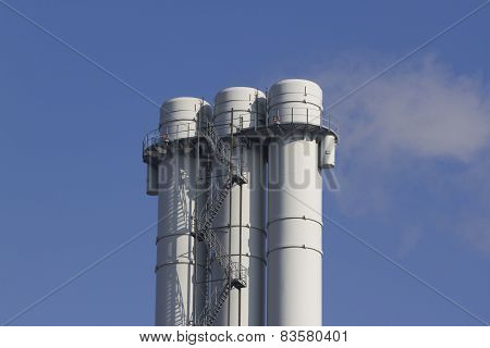 triple tube emits smoke against the blue sky