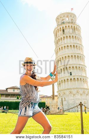Funny Young Woman Supporting Leaning Tower Of Pisa, Tuscany, Italy