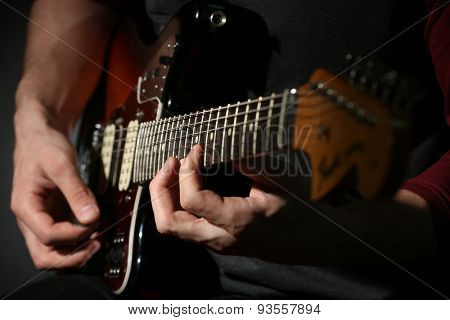 Young man playing on electric guitar close up