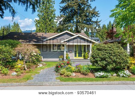 Cozy house with green door and beautiful landscaping on a sunny day with mountains in the background
