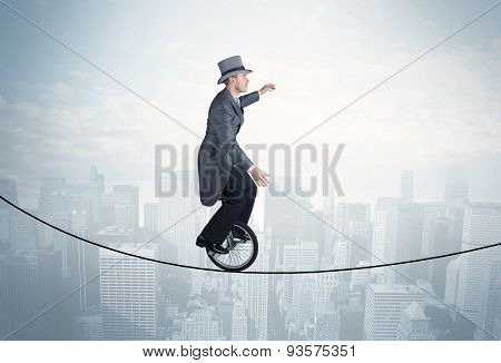 Brave guy riding a monocycle on a rope above cityscape concept