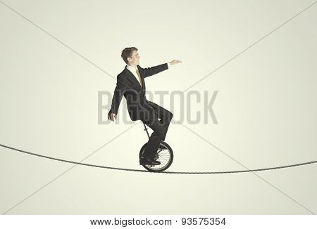 Brave business man riding an mono cycle between cliffs concept