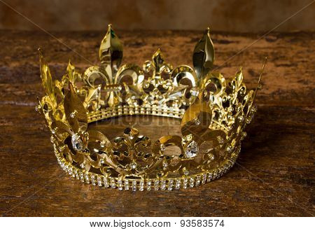 Medieval style golden crown on antique wooden background