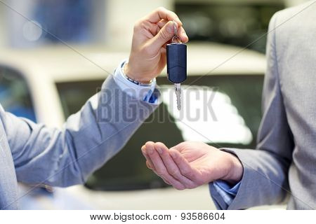 auto business, car sale, deal and people concept - close up of male hands with car key in auto show or salon