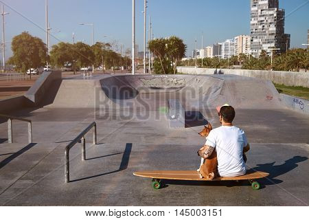 Longboarder In Skate Park With His Dog