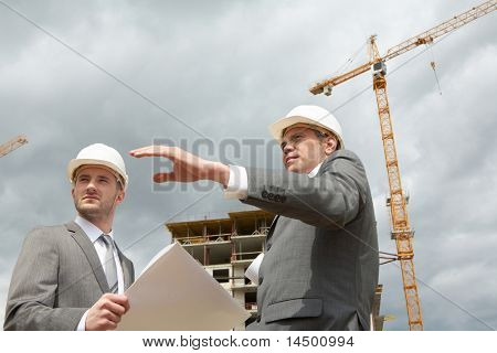 Photo de confiance ingénieur montrant quelque chose à son associé au chantier