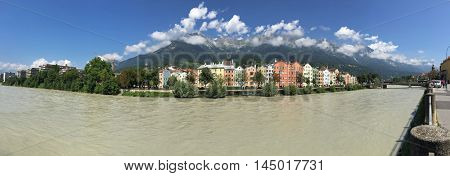 Panoramic view of colorful buildings and mountains along Inn river in Innsbruck city. Panorama of capital of Austria, Europe during summer time. Inn River is a right tributary of the Danube