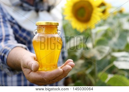 Man holding bottle of honey on sunflower field background