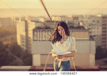 Beautiful young girl at the roof with origami paper crane in hands. Vintage tinted selective focus.