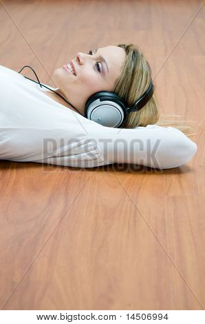 junges Mädchen hören entspannenden Musik mit Kopfhörer auf hölzernen Boden liegend