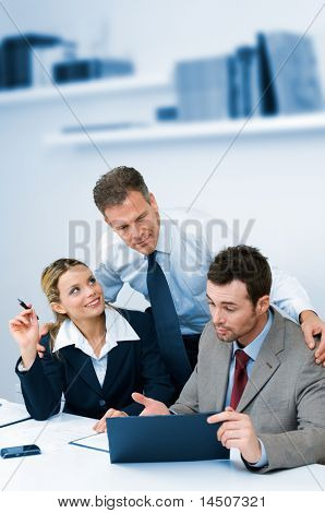 Satisfied mature manager supervising and collaborate with his business team in modern office
