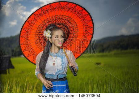 Beautiful asian girl in Myanmar traditional costume with Red bamboo umbrella on on Rice fields Sky background identity culture of Thailand