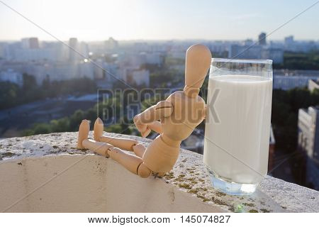 puppet with glass of milk sitting on balcony