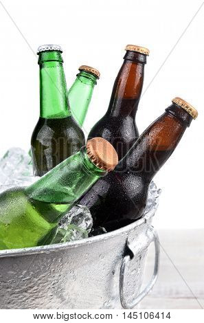Closeup of green and brown beer bottles in a metal ice bucket. 