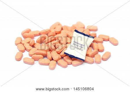 Desiccant pack on a pile of vitamin C tablets / Using silica gel with medicine to prevent humidity