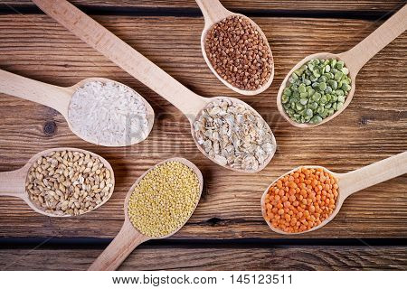 Grains in the spoon, a wooden spoon, a range of cereals, a table of old wood, the grain harvest, organic food, cereal close-up, texture of old wood, kitchen utensils, healthy food.