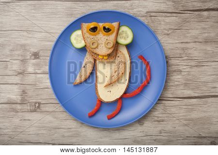 Monkey made of bread cheese and vegetables on wooden background and plate