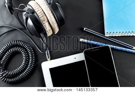 blank notebook in top view with music concept Black background headphones