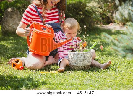 Pregnant woman with little daughter in the summer orchard cearing flower.