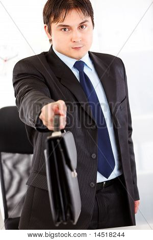 Hombre de negocios autorizada en escritorio de oficina y dando el maletín. Close-up.