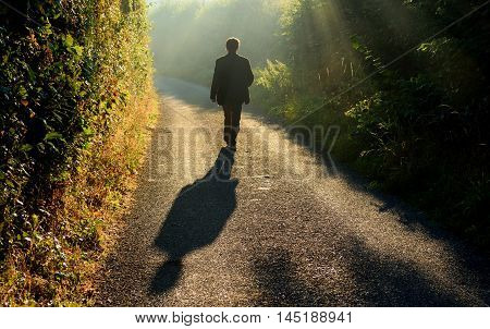 Alone man walking along a small country road in a misty morning