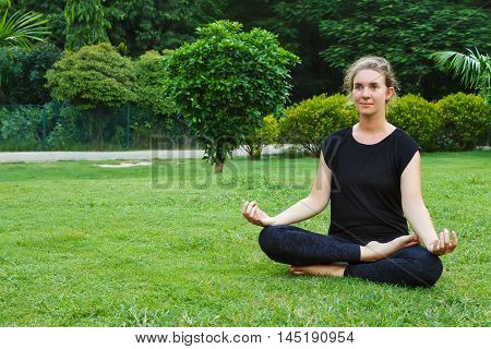 Woman in lotus poisture in green garden