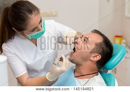 Dentist giving an injection of anesthesia to the patient. Young man at the dental clinic