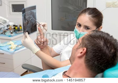 Image of young patient and dentist showing him x-ray radiography, in the Dental Clinc