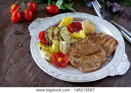 Grilled Steak Meat Pork And Grilled Vegetables On Brown Stone Background. Copy Space.