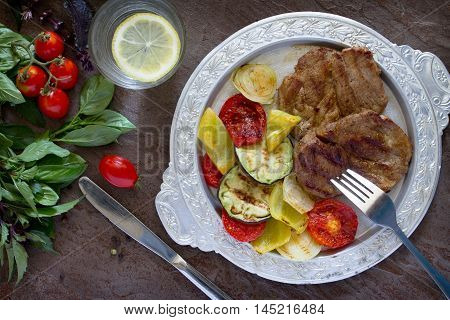 Grilled Steak Meat Pork And Grilled Vegetables On Brown Stone Background. Top View .