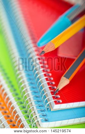 Closeup shot of pensil against defocused notebooks in background. Focus on the tip of grey pencil.
