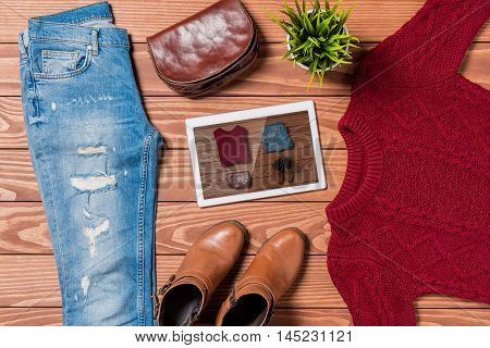 Digital tablet and autumn clothes on wooden table. Online shopping concept