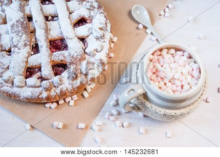 Autumn snack: hot chocolate with marshmallows and сherry pie on a light background