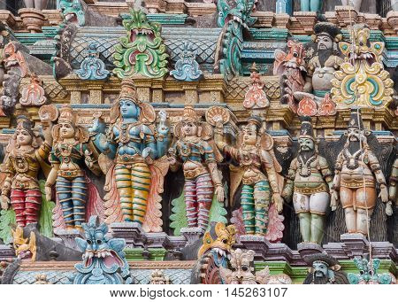 Madurai India - October 19 2013: Closeup of Lord Vishnu with his two wives Lakshmi and Bhu. One servant on each side. Few other figures. Facade of the South Gopuram at Meenakshi Temple.